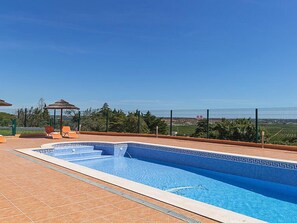 Une piscine dont le carrelage présente un motif géométrique, entourée d’une clôture et agrémentée d’un belvédère.