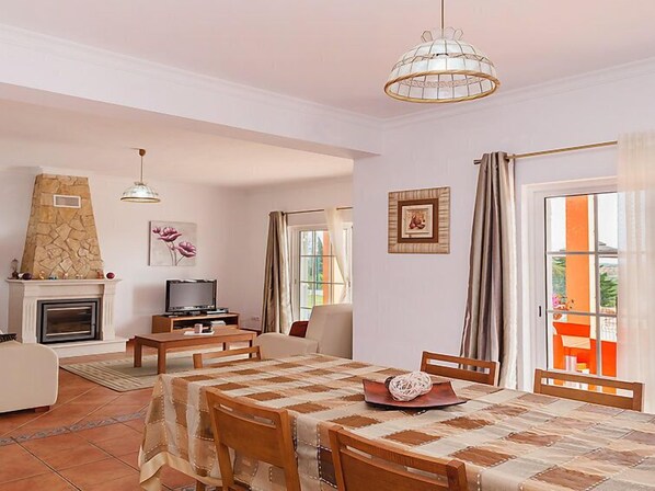 A cozy living room with a fireplace, a dining table, and a TV.