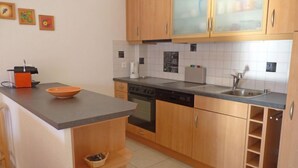 A kitchen with wooden cabinets, a dishwasher, a sink, and a countertop with a bowl. - Viognier 5 by Interhome (Ovronnaz)