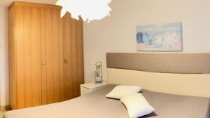 A bedroom with a bed, bedside table, and a wooden wardrobe. - Viognier 5 by Interhome (Ovronnaz)