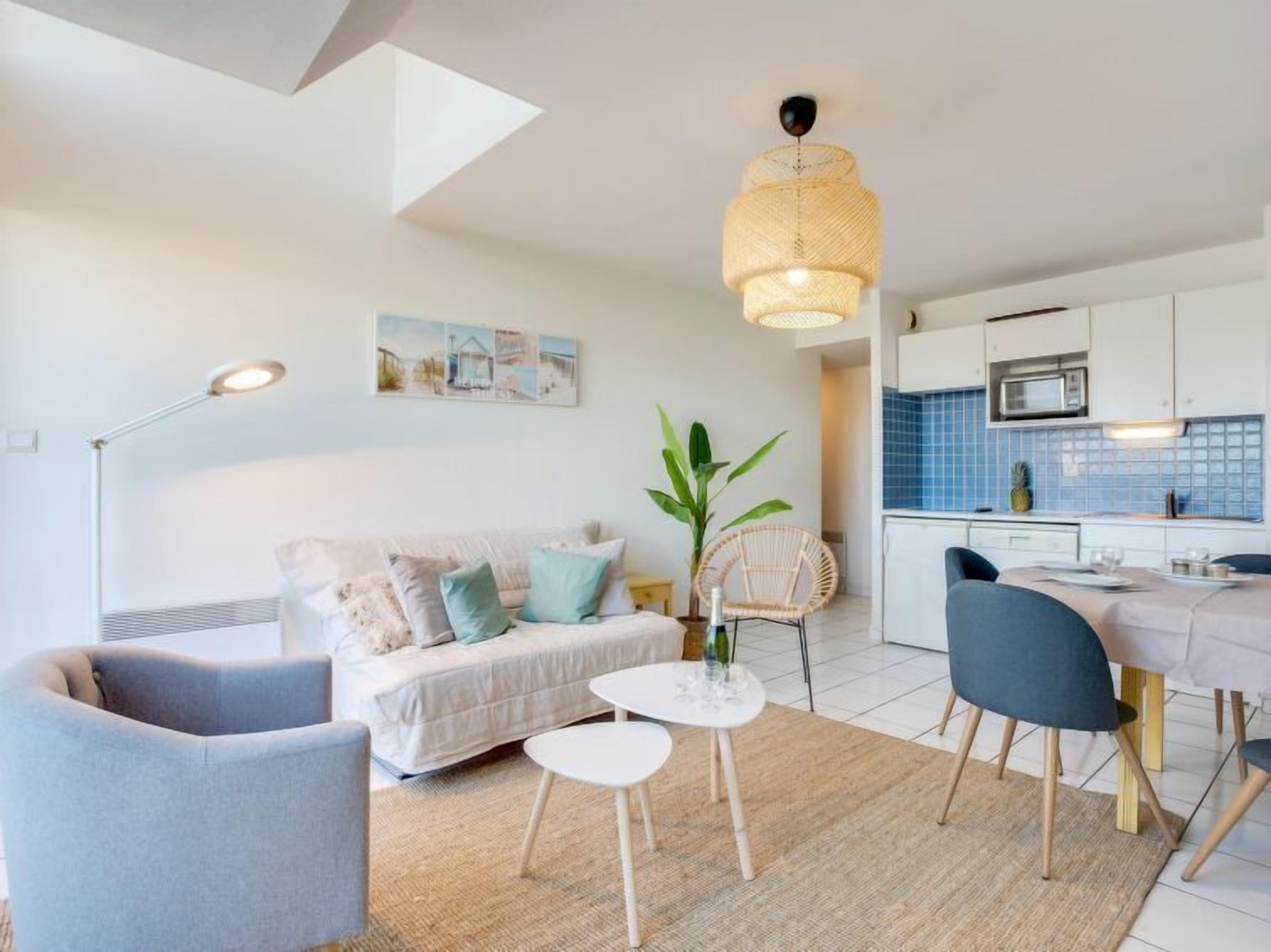 A modern living room with a sofa, a dining table, and a kitchen area.