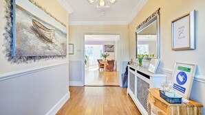 A hotel lobby with a wooden floor, a reception desk, a mirror, and a framed sign on the wall. - The Coast House B&B (Bognor Regis)