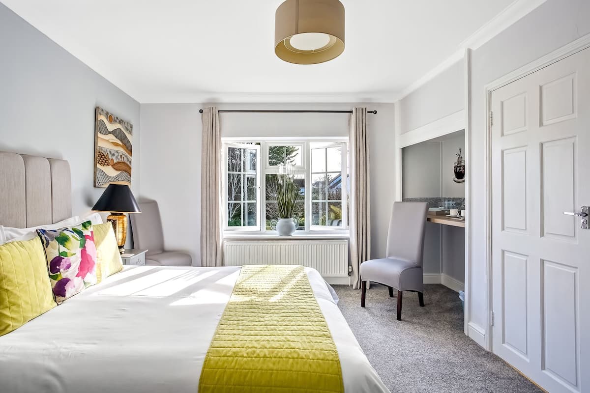 Un dormitorio con cama, escritorio, silla, ventana y radiador.