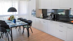 A modern kitchen with white cabinets, a black countertop, and a dining area with a table and chairs. - LaVille B-1-2 by Interhome (Locarno)