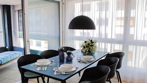 A modern dining area with a table set for four, a large window with sheer curtains, and a view of the outside. - LaVille B-1-2 by Interhome (Locarno)