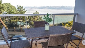 A balcony with a table and chairs, overlooking a body of water and trees. - Terrasses d'Emeraude by Interhome (Dinard)