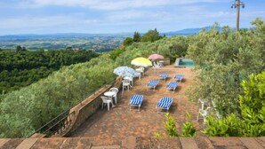 Une terrasse dotée de chaises longues et de parasols, offrant une vue sur un paysage magnifique.