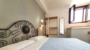 Quarto com cama, guarda-roupa, espelho e janela.
