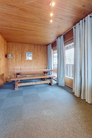 A room with wooden walls, a bench, a window with curtains, and a ceiling light. - La Grande Casse (Lavachet) by Interhome (Tignes)