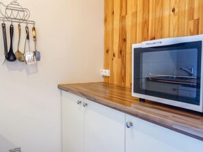 Une cuisine avec un four blanc, un plan de travail en bois et un étagère contenant des ustensiles de cuisine.