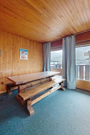 A wooden interior with a picnic table, a poster on the wall, and a view through a window. - La Grande Casse (Lavachet) by Interhome (Tignes)