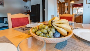 Un comedor con una mesa de madera, un cuenco de fruta y sillas.