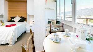 A hotel room with a bed, bedside table, and a dining area with a table set for two. - Roses Holiday Center by Interhome (Roses)