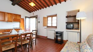Una cocina acogedora con armarios de madera, una mesa de comedor con sillas, un televisor y un sofá.