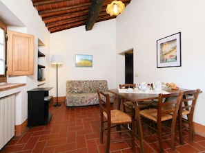 A cozy dining area with a wooden table and chairs, a sofa, and a lamp.