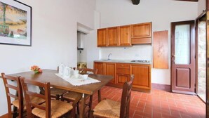 Un comedor con mesa y sillas de madera, una cocina con armarios de madera y un suelo de baldosas rojas.
