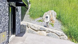 A building with a stone facade and a green roof, a stone pathway leading to a door, and a digital device on a rock. - Apartment Erika by Interhome (Kappl)