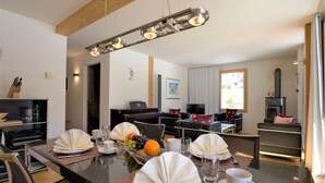 A modern dining area with a central island, a piano, and a fireplace. - Chesa Lej by Interhome (Pontresina)