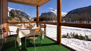 A wooden deck with a table set for two, overlooking a snowy landscape with mountains. - Chesa Lej by Interhome (Pontresina)