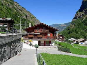 A mountain lodge with a balcony, a stone wall, and a view of the valley. - Christl by Interhome (Stalden)