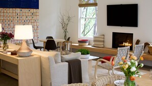 Un salon moderne comprenant un canapé, des fauteuils, une table basse, un téléviseur et une cheminée.