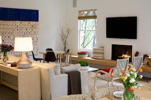 Un salon moderne comprenant un canapé, des fauteuils, une table basse, un téléviseur et une cheminée.