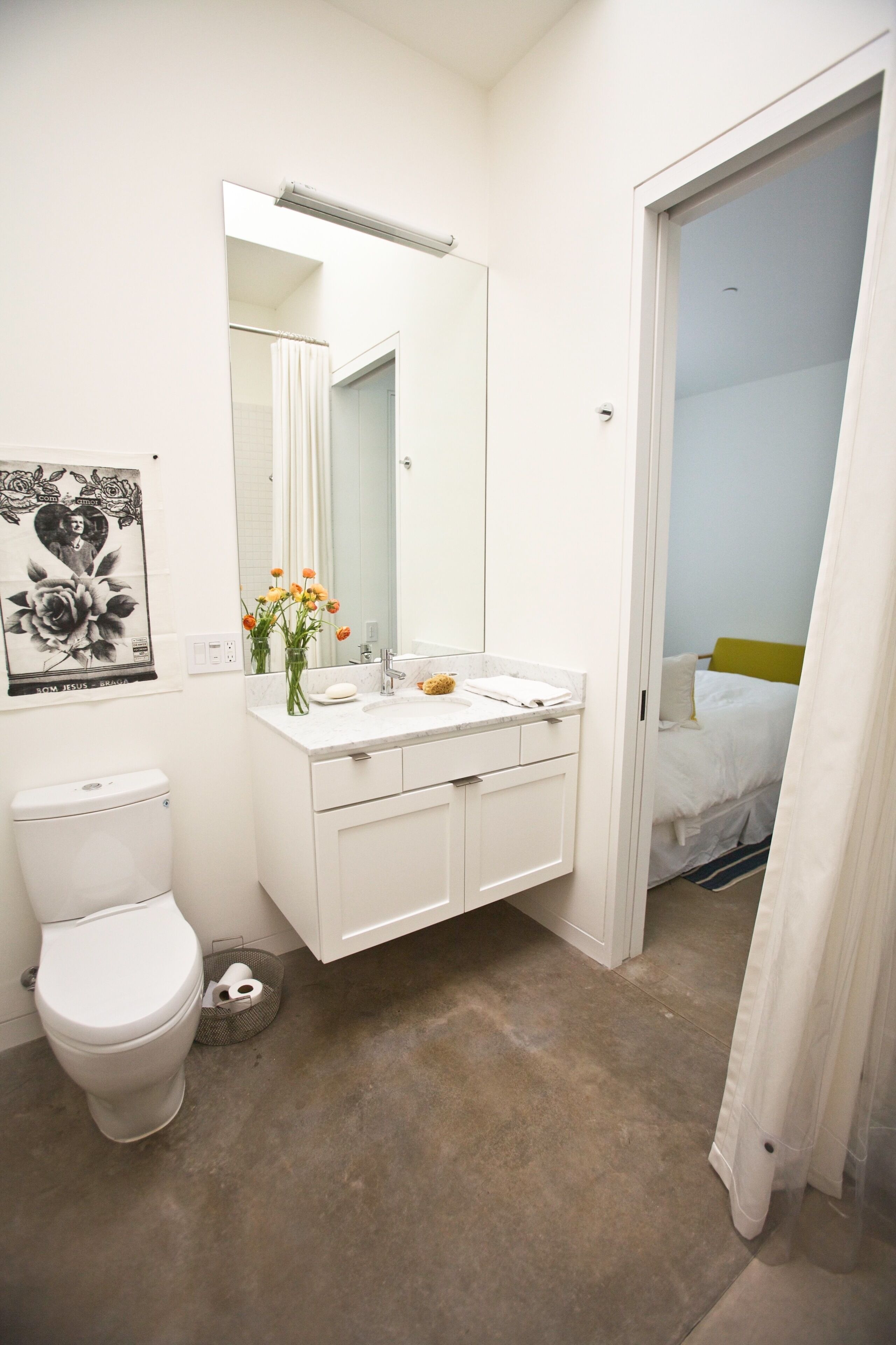 Ein Badezimmer mit Toilette, Waschbecken, Spiegel und Duschbereich.