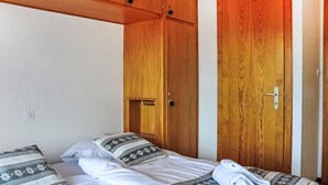 Una cama individual con ropa de cama estampada, un armario de madera y una puerta con picaporte.