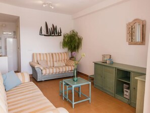 Un salon avec un canapé à rayures, une petite table, un meuble et un élément décoratif mural.