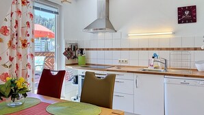 A modern kitchen with white cabinetry, a stainless steel range hood, and a wooden countertop.