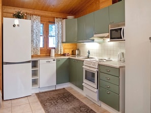 Cocina compacta con refrigerador, lavavajillas, estufa, microondas y una ventana con cortinas.