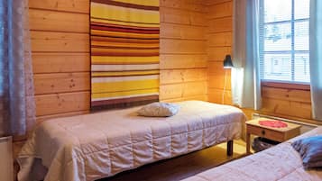 Una habitación tipo cabaña con dos camas, una lámpara y una ventana con persianas.