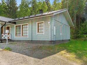 Ett envåningshus med ett sluttande tak, en veranda och en grusuppfart.