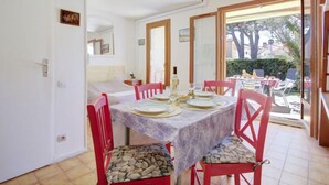 A dining area with a table set for four, red chairs, and a view of the outdoors through large windows.