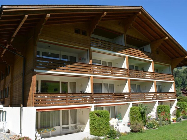 A multi-story wooden chalet with balconies, a covered outdoor seating area, and a well-maintained garden.