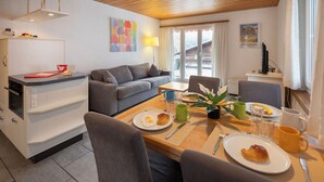 Eine moderne Küche mit Essbereich, ausgestattet mit Holzbalkendecke, grauem Sofa und Frühstückstisch.