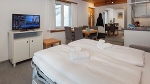 Ein Hotelzimmer mit Bett, Fernseher, Schreibtisch und Essecke.