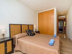 Ein Schlafzimmer mit Bett, Nachttisch, Kleiderschrank und einem zur anderen Kammer führenden Gang.