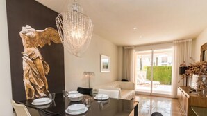 Un coin repas avec une table dressée pour quatre personnes, un lustre et une statue accrochée au mur.