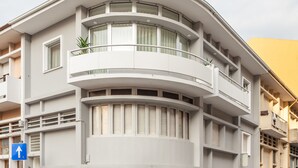 En modern byggnad med en böjd balkong, flera fönster och en tydlig blåriktad skylt.