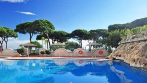 A clear blue pool with steps leading in, surrounded by trees and a rocky wall. - Windsor by Interhome (Blanes)