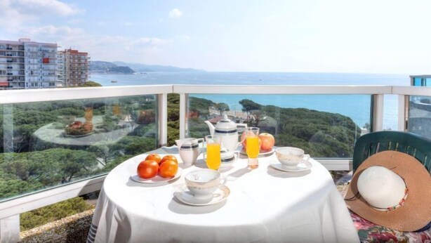 A table set for breakfast with a view of the sea and buildings in the background. - Windsor by Interhome (Blanes)