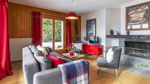 A cozy living room with a sofa, armchair, and a fireplace. - Brocard by Interhome (Val-d'Illiez)