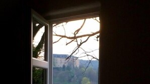 A room with a large window overlooking a red building and a green landscape. - Ferienwohnung Teufelsmauer Waldhaus (Blankenburg)