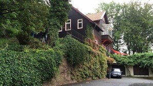 A house with a steeply sloped roof, a garage, and a car parked in front. - Ferienwohnung Teufelsmauer Waldhaus (Blankenburg)