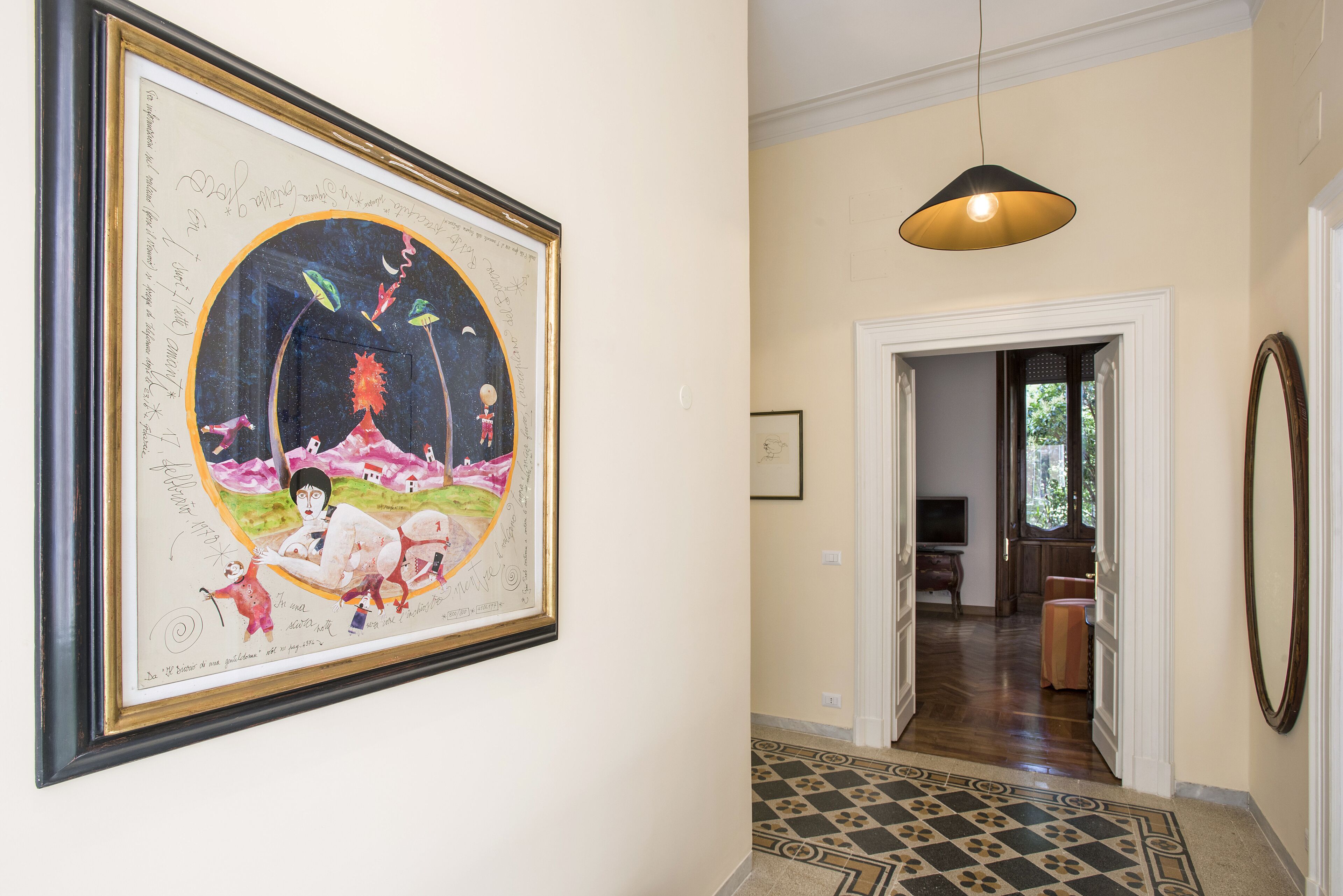A hallway with a framed artwork, a patterned rug, and a hanging pendant light.