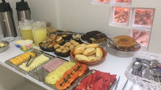 A buffet with various food items including fruits, pastries, and condiments. - Pousada Pai Nosso (Aparecida)