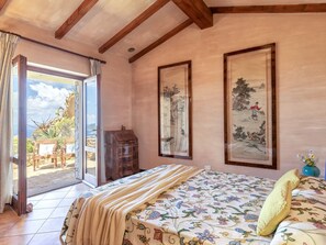 A bedroom with a bed, a wooden dresser, and two framed paintings on the wall.
