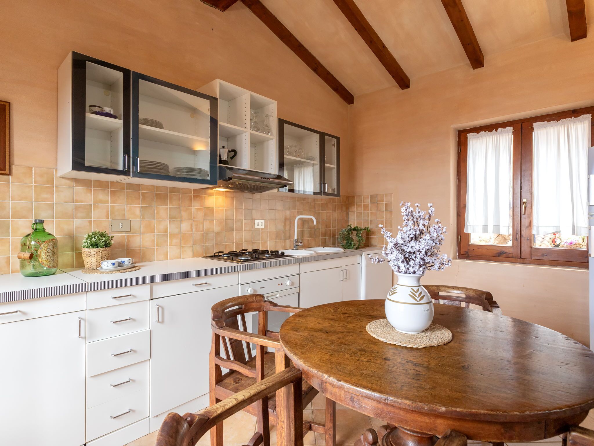 A kitchen with white cabinets, a stove, and a dining table with chairs.