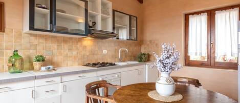 A kitchen with white cabinets, a stove, and a dining table with chairs.